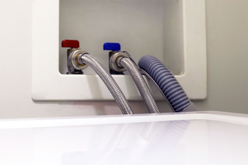 Image of stainless steel washing machine hoses connecting to a machine