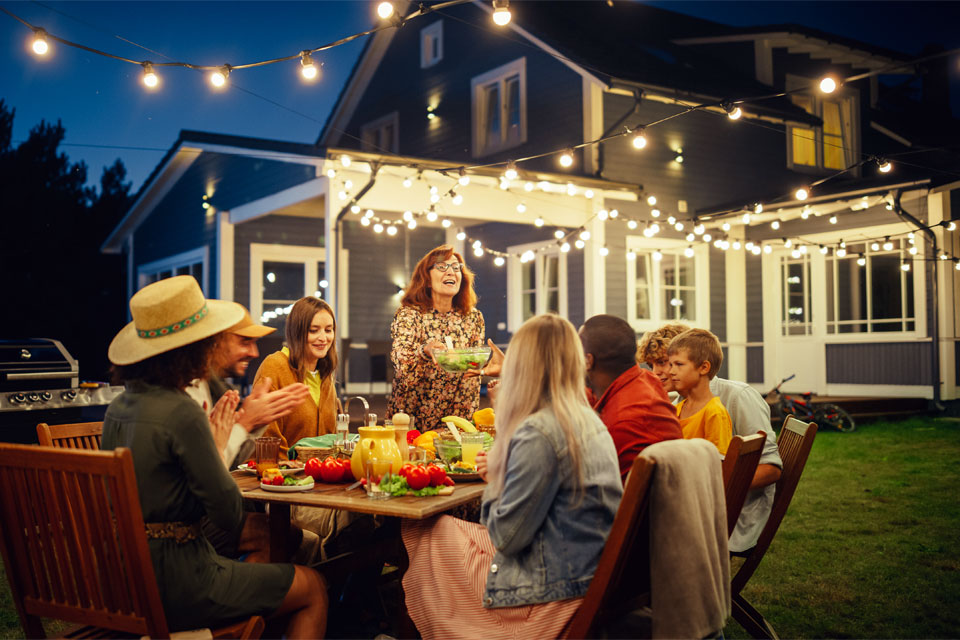 Image of a group of happy friends eating dinner in the backyard
